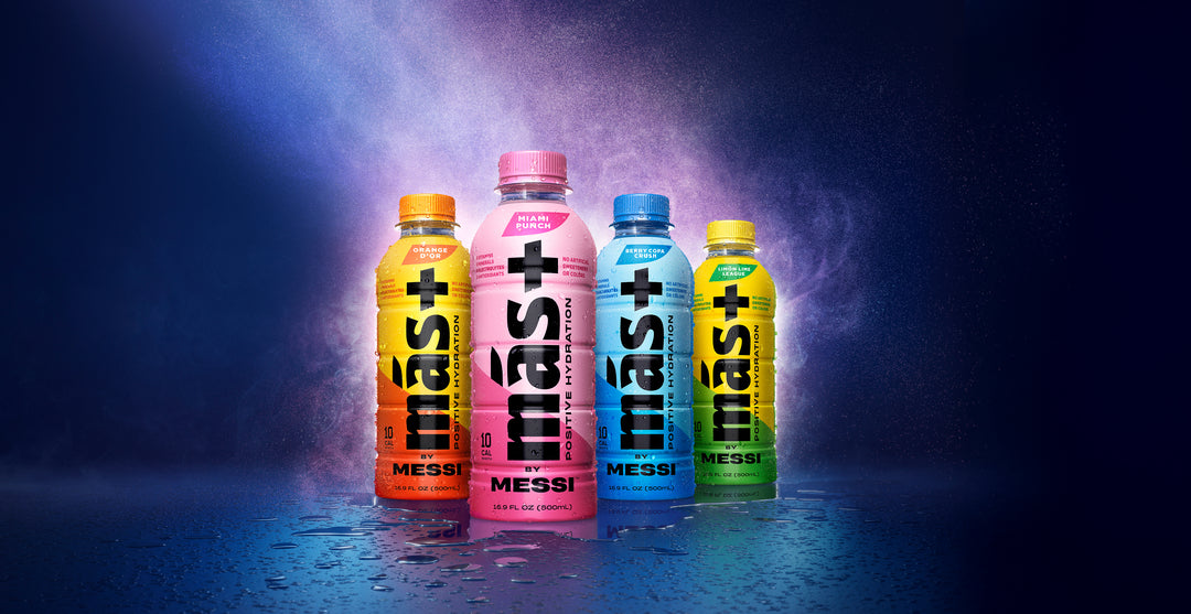 Más+ by Messi drink bottles in various flavors, arranged in front of a dramatic, colorful mist.