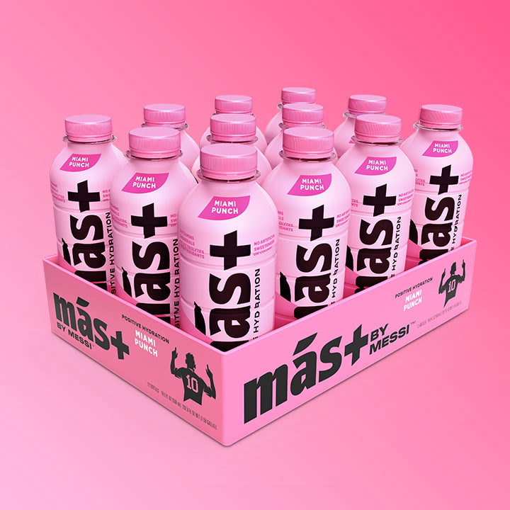 A neatly arranged 12-pack of protein drinks in pink bottles with pink caps, featuring the bold black text "Más+" and the brand "Messi." The packaging is light pink with black branding, and the background has a gradient pink effect.