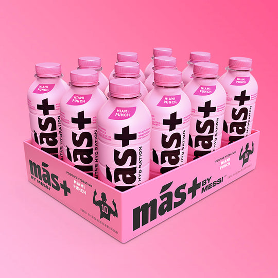 A neatly arranged 12-pack of protein drinks in pink bottles with pink caps, featuring the bold black text "Más+" and the brand "Messi." The packaging is light pink with black branding, and the background has a gradient pink effect.