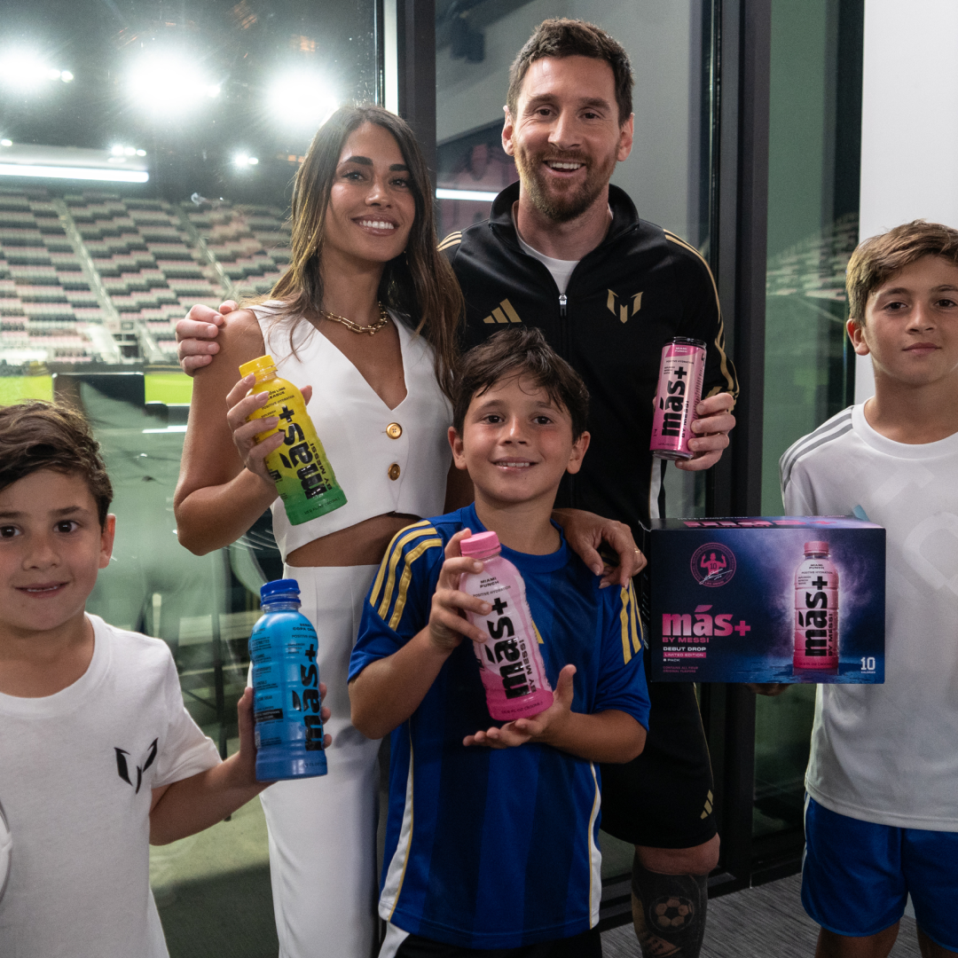 Leo Messi, alongside his wife Antonela and their three sons, proudly holding various Más+ by Messi products.