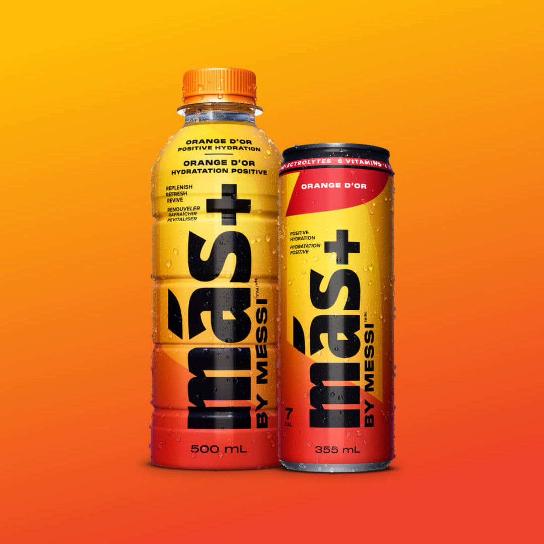 Two beverages labeled Más+ by Messi against an orange gradient background. The left bottle is 500 mL with an orange cap, and the right can is 355 mL. Both drinks are 'Orange d'Or' flavour and promote 'positive hydration' with electrolytes and vitamins