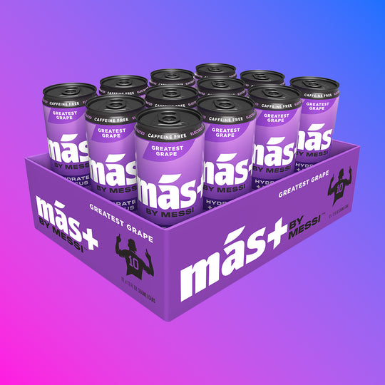 A purple cardboard tray holding twelve cans of Más by Messi Greatest Grape flavored, caffeine-free drink.