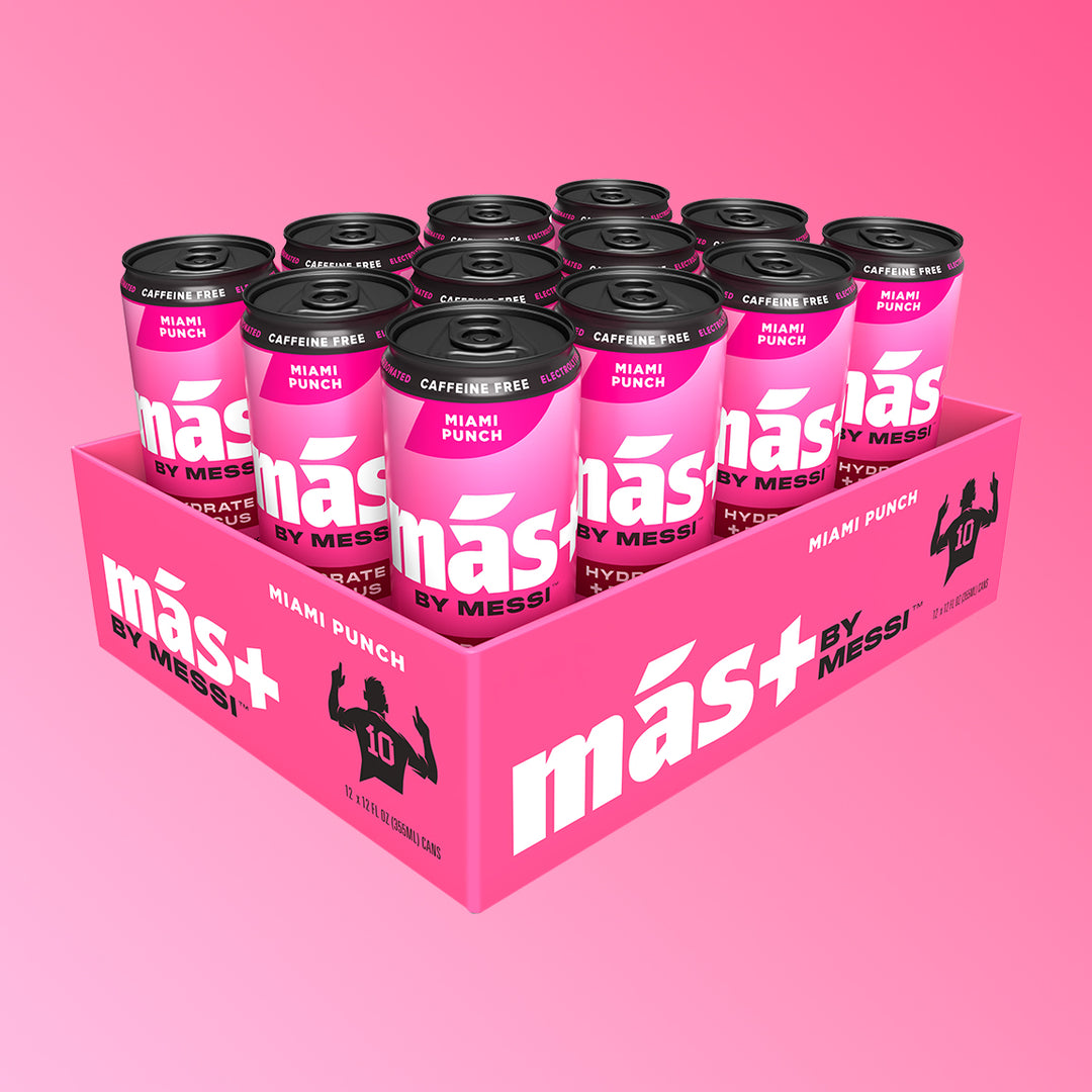 A pink cardboard tray holding twelve cans of Más by Messi Miami Punch flavored, caffeine-free sports drink.